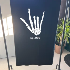 Navy fleece blanket with the large ily...DBS skeleton hand, displayed on a stand