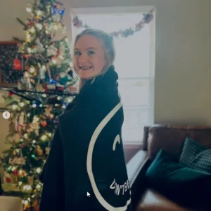 Girl wrapped in the oversized navy DON'T BE SHITTY smiley blanket, showing its full size