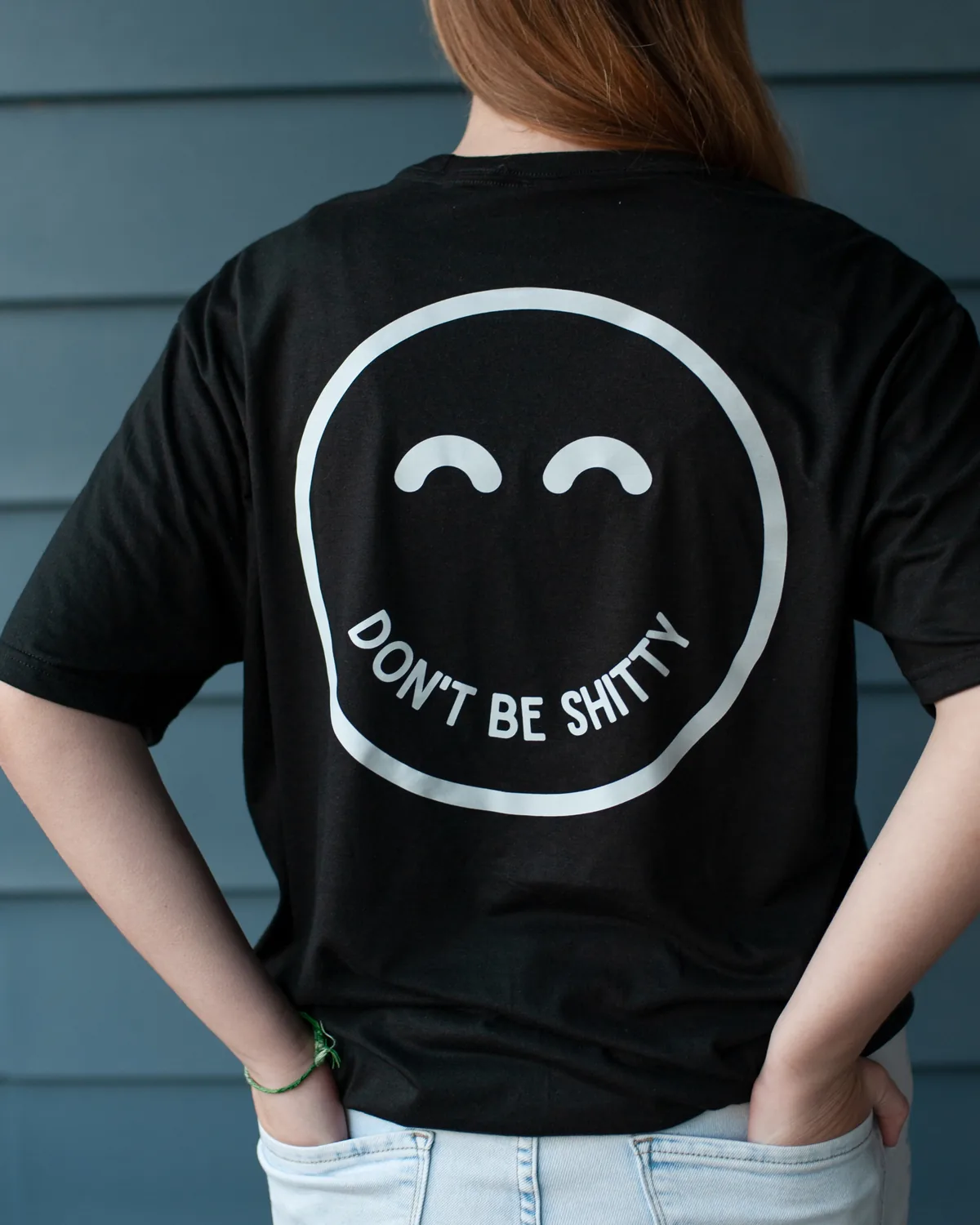 Back view of the black DON'T BE SHITTY smiley t-shirt being worn